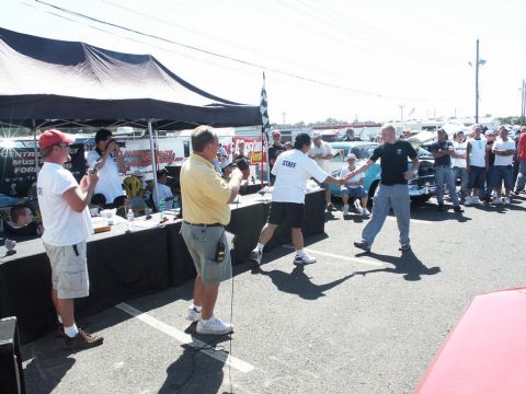 2001 Mercury Grand Marquis - A car show event is underway with attendees and staff interacting near a table and tents.