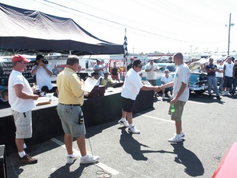 2001 Mercury Grand Marquis - Attendees gather at a car show for an award ceremony, with a vintage car visible behind the participants.