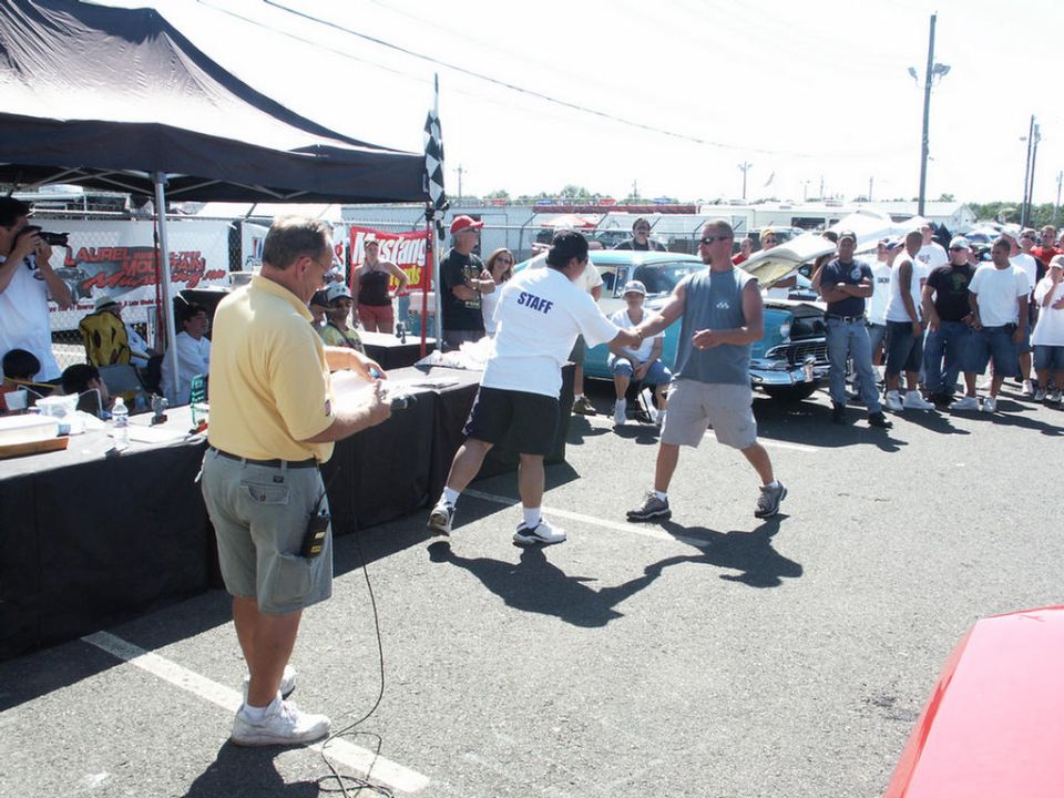 People gathered at a car show, with a blue classic car in the background