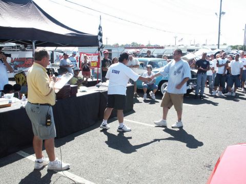 2001 Mercury Grand Marquis - A car show event is underway with an award being presented to a participant in front of a classic blue automobile.