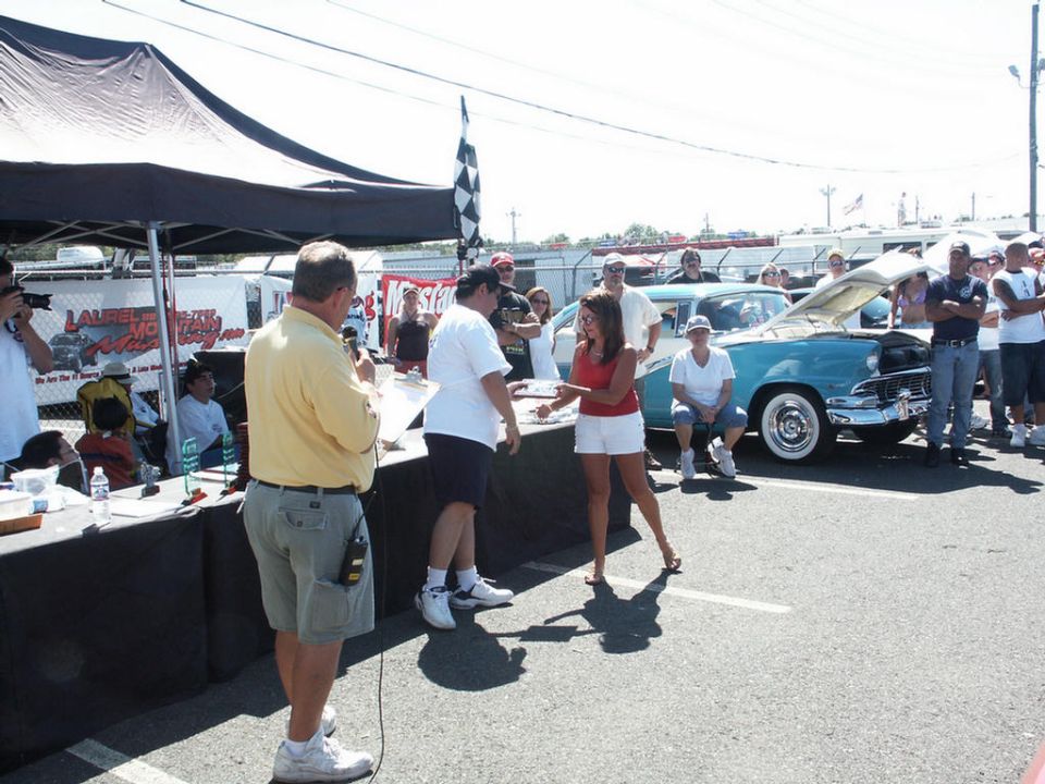 Turquoise 1956 classic car with hood open at car show, people gathered around