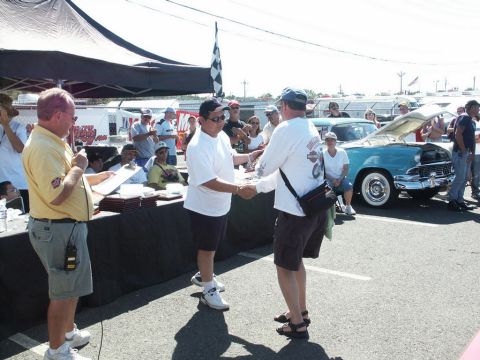 2001 Mercury Grand Marquis - People gather at a car show, with one person receiving an award in front of a vintage automobile.