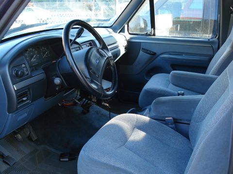 1994 Ford Bronco - The interior of a 1994 Ford Bronco features blue cloth seats, a dashboard with gauges, and a steering wheel.