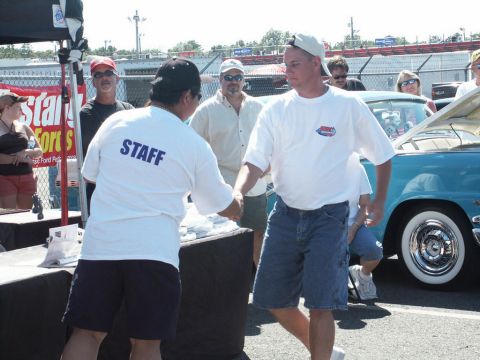 2001 Mercury Grand Marquis - People gather at an outdoor event, with a vintage car on display and staff members interacting.