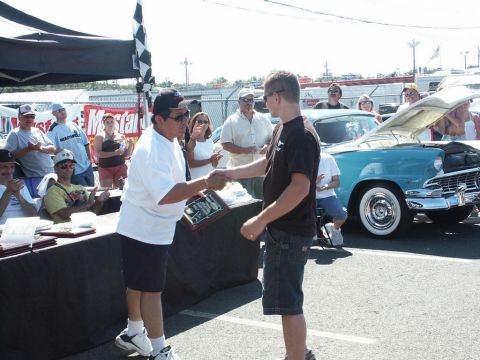 2001 Mercury Grand Marquis - A man receives an award at a car show with a vintage turquoise car visible.