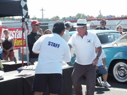 2001 Mercury Grand Marquis - Attendees and staff interact at an outdoor car show event, with a vintage car in the background.