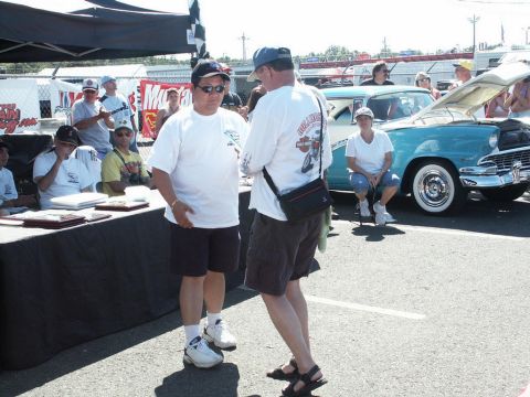 2001 Mercury Grand Marquis - Attendees gather around a vintage turquoise and white car with its hood up at an outdoor event.
