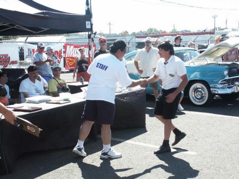 2001 Mercury Grand Marquis - An outdoor event appears to be a car show, with staff members interacting and a classic car on display.