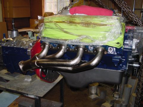 1979 Ford Bronco - Engine part shown covered in plastic and hanging from chains in a workshop setting.