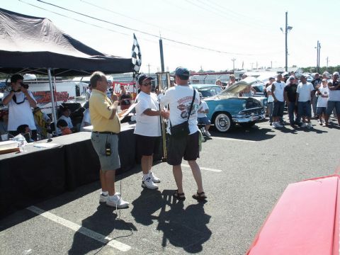 2001 Mercury Grand Marquis - An award is presented at an outdoor car show event, with several spectators and classic vehicles visible.