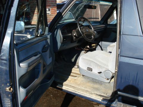 1994 Ford Bronco - The interior of a blue SUV is shown with the driver's door open, revealing the dashboard and seating area.
