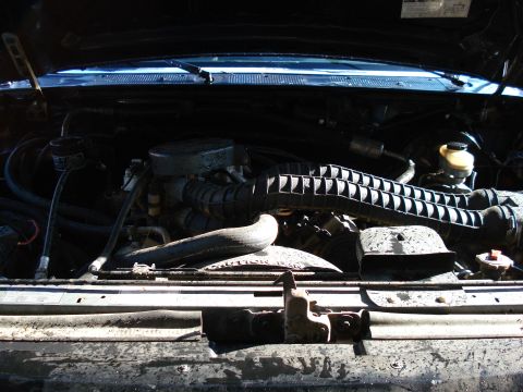 1994 Ford Bronco - The engine bay of a vehicle is shown with various components and hoses.