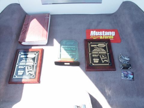 2001 Mercury Grand Marquis - Awards and a book are displayed on a carpeted surface, possibly a car trunk.