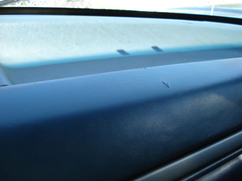 1994 Ford Bronco - Close-up of a vehicle's dashboard surface, showing a minor scratch. The image includes a watermark for SUPERMOTORS.