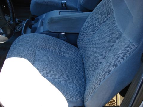 1994 Ford Bronco - The interior of a vehicle features blue patterned fabric seats and a center console with an armrest.