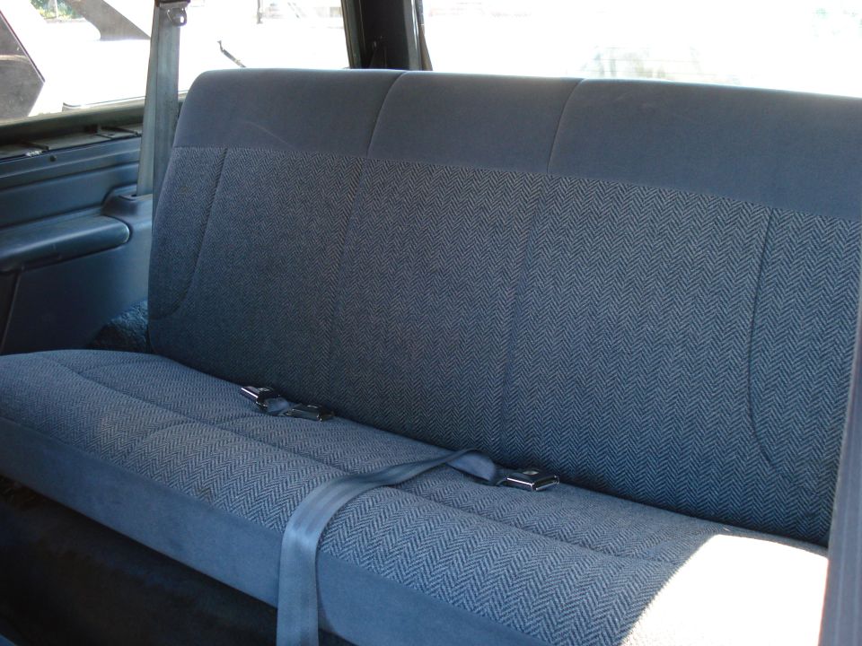 Blue patterned rear bench seat with seatbelts in a vehicle