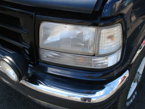 1994 Ford Bronco - Close-up of the front headlight and bumper assembly on a black truck, identified as a 1994 Ford Bronco.
