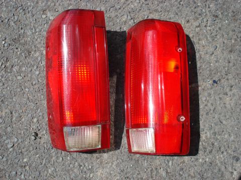 1994 Ford Bronco - Pair of red taillights for a vehicle, shown on a gray asphalt surface.