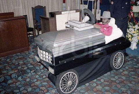 2000 Ford Crown Victoria - A custom coffin designed to resemble a car, complete with wheels and a mannequin figure.