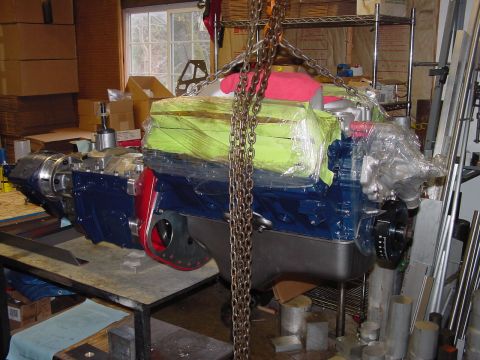 1979 Ford Bronco - A blue engine and transmission assembly is being hoisted by chains in a workshop setting.
