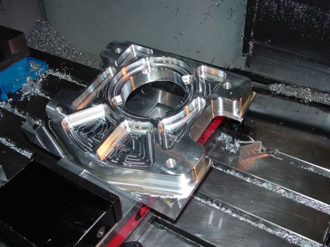 1979 Ford Bronco - A custom-machined metal component sits on a CNC machine, surrounded by metal shavings from the manufacturing process.