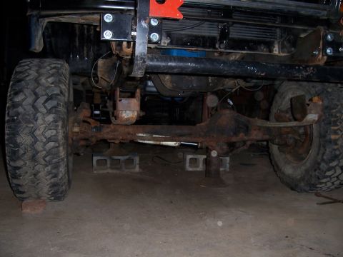1983 Ford Bronco - Close-up view of the front axle and suspension of a vehicle, showing significant rust and modifications.