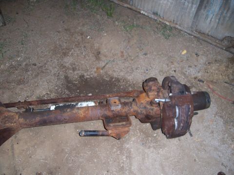 1983 Ford Bronco - A rusty Dana 60 axle assembly is shown, likely a front axle, with its brake caliper visible.