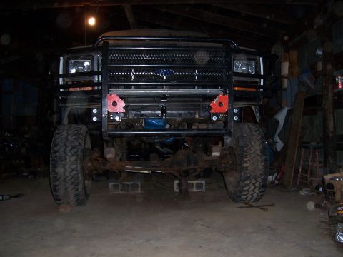 1983 Ford Bronco - This Ford Bronco is on jack stands in a garage, showing its front end with a large grille guard.
