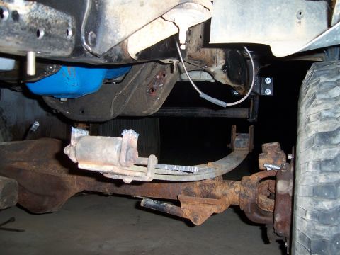 1983 Ford Bronco - Close-up view of the rusty undercarriage of a vehicle, focusing on the suspension components.
