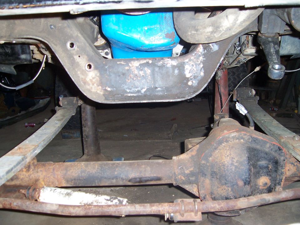 Undercarriage of a vehicle with a blue oil pan and rusty differential