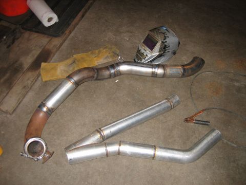 1969 Ford Mustang - Custom exhaust pipes and welding gear are assembled on a workshop floor, ready for installation.