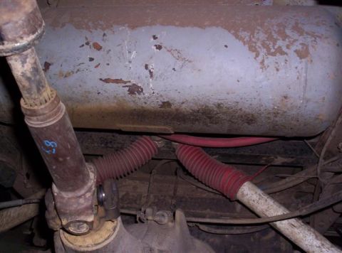 1995 Ford Bronco - Underside view of a driveshaft and fuel tank with red bellows hoses.
