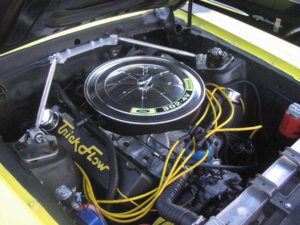 Yellow engine bay showing a Ford 302-4V Boss engine with Trick Flow valve covers and yellow spark plug wires