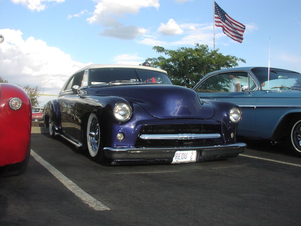 Purple customized coupe with a white roof and wide tires, parked next to a blue car