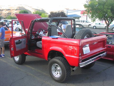 1979 Ford Bronco - A red 1978 Ford Bronco is parked with its doors and hood open, revealing its interior and engine bay.