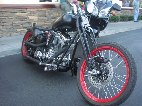1979 Ford Bronco - A custom black motorcycle with striking red spoke wheels is parked outdoors.