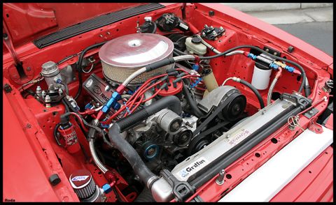 1993 Ford Mustang - The engine bay of a red 1993 Ford Mustang shows a modified engine with custom components and vibrant red paint.