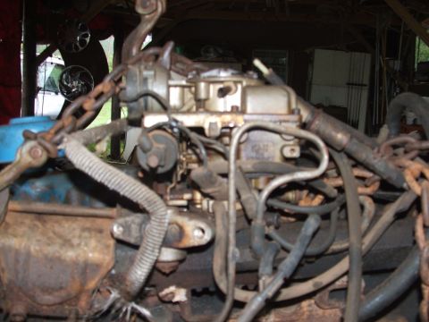 1966 Ford Ranchero - Close-up view of an engine's carburetor and associated hoses, suspended by chains.