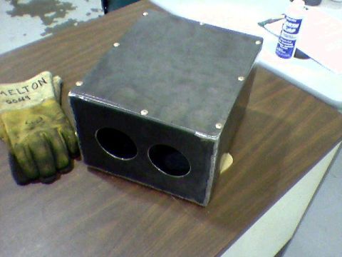 1988 Ford Bronco - A metal fabrication with two openings sits on a wooden surface next to a work glove.