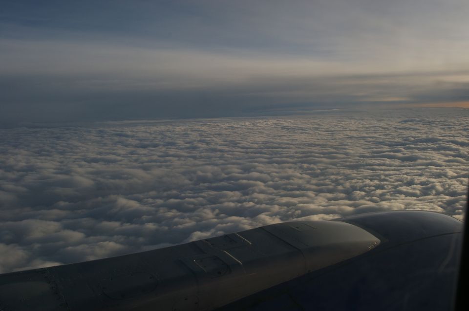 View from airplane window showing wing and clouds below