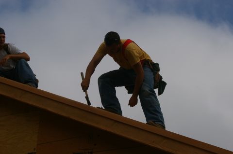 1998 Jeep TJ - Construction workers are seen on a rooftop under a cloudy sky.