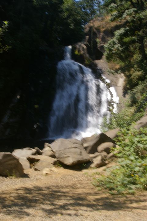 1998 Jeep TJ - A scenic waterfall flows down a rocky cliff face, surrounded by lush green trees and vegetation.