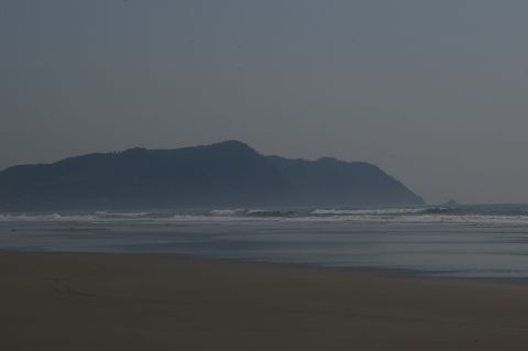1998 Jeep TJ - A wide shot of a beach and ocean with hills in the background, under a muted sky.