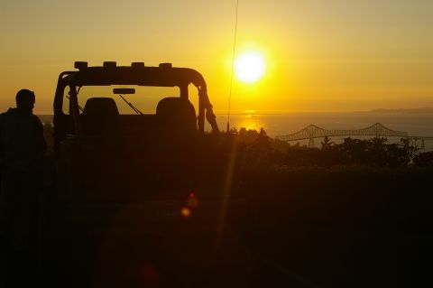 1998 Jeep TJ - A person stands beside a Jeep Wrangler during a sunset overlooking a bridge and the ocean.
