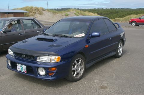 1998 Jeep TJ - This blue Subaru Impreza coupe, seen near sand dunes, does not match the registry's claim of a 1998 Jeep TJ.