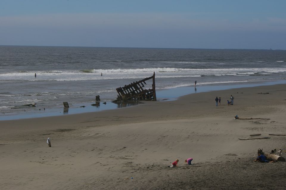 Shipwreck on a sandy beach with people walking and children playing