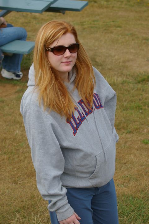 1998 Jeep TJ - A woman stands outdoors wearing a grey hoodie and sunglasses.