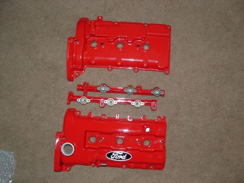 1995 Ford Probe - Red painted Ford engine parts, including valve covers and fuel rails, are laid out on a carpeted floor.