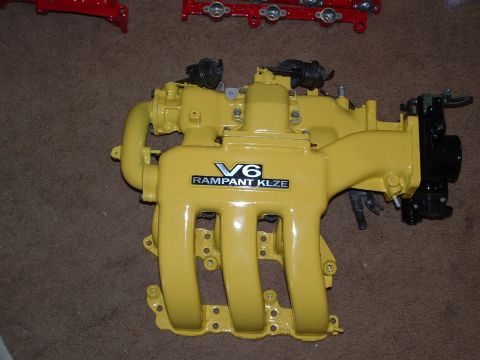 1995 Ford Probe - A yellow V6 intake manifold, labeled "V6 RAMPANT KLZE", is shown against a brown carpet background.