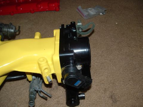 1995 Ford Probe - Close-up of a yellow intake manifold and black throttle body assembly, likely a car part.